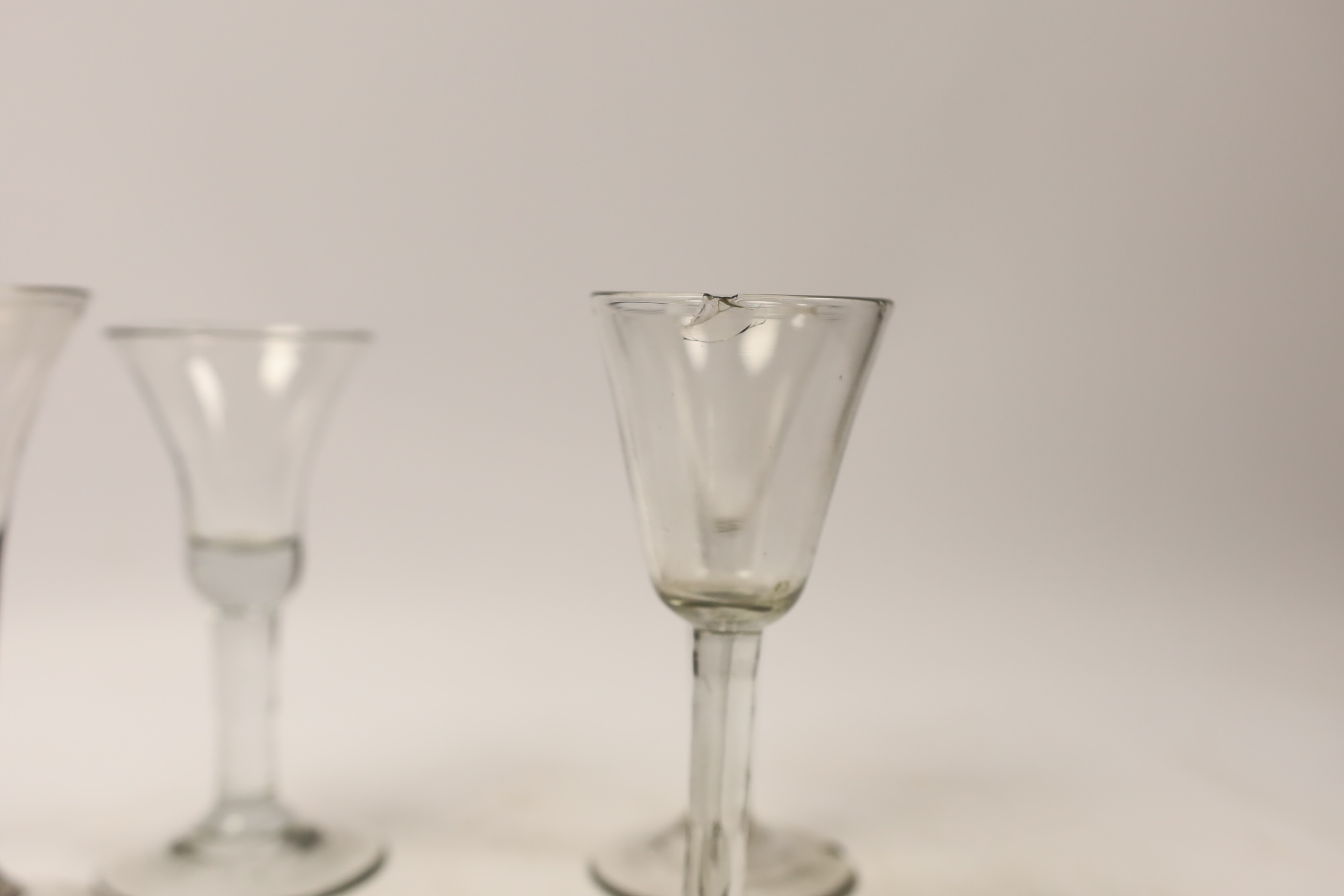 Five mid-18th century plain stem wine glasses, including three with drawn trumpet shaped bowls, two examples with folded feet, tallest 16cm